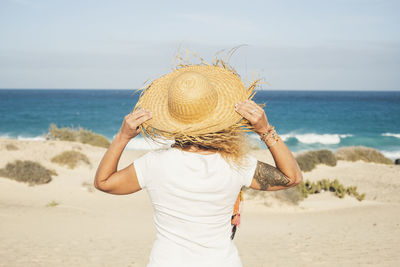 Rear view of woman on beach against sky