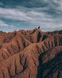 Bird on rock formations against cloudy sky