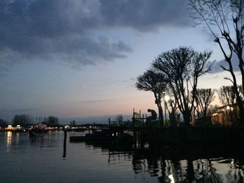 Reflection of trees in water against sky at night