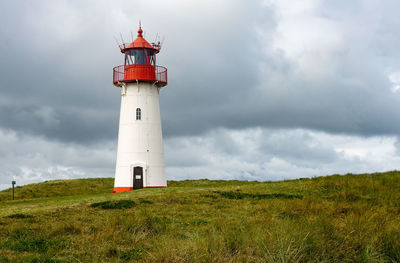 Lighthouse on field against sky