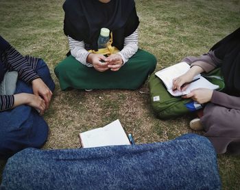 Low section of people sitting on field