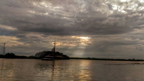 Traditional windmill by sea against sky during sunset