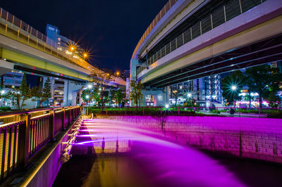 Illuminated bridge over river in city at night