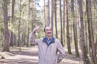 Portrait of smiling young woman standing in forest