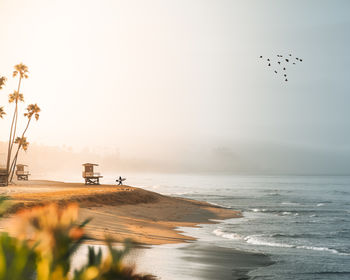 Scenic view of sea against sky with a surfer on the beach
