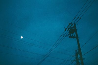 Low angle view of electricity pylon against sky at night