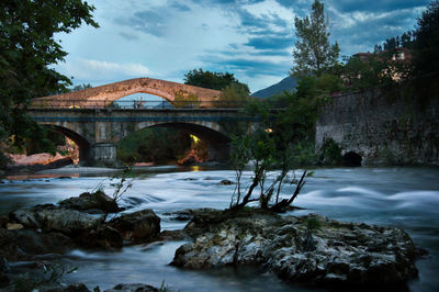 Arch bridge over river against sky