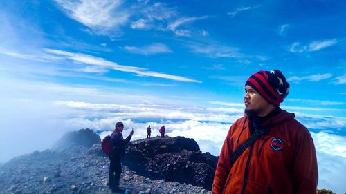 Friends standing on mountain against sky