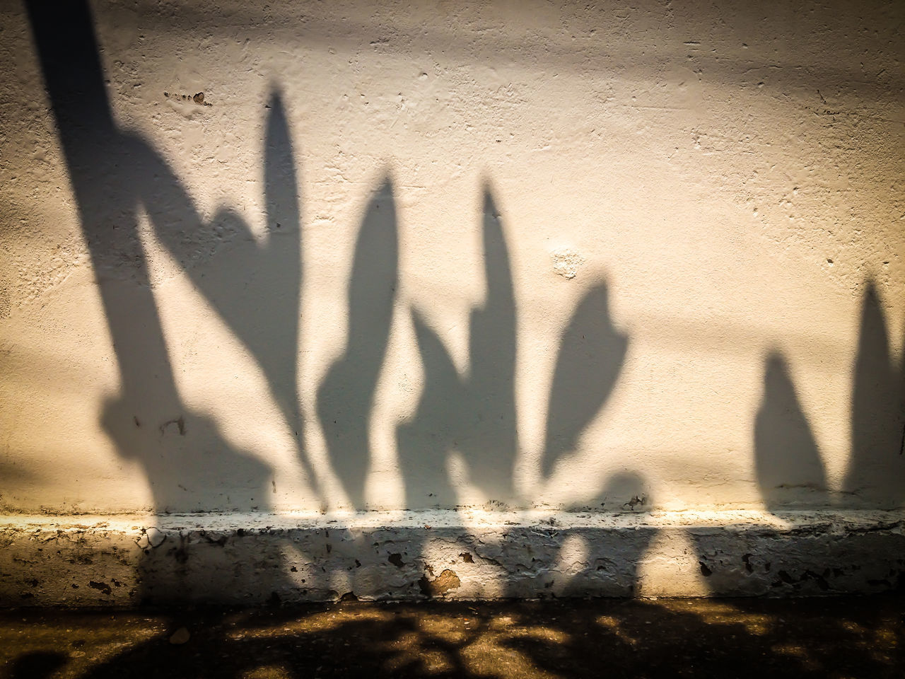 SHADOW OF PEOPLE STANDING ON WALL WITH GRAFFITI