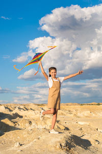 Rear view of woman jumping at beach against sky