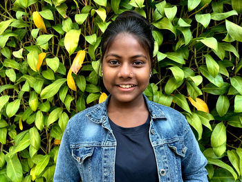 Portrait of young woman standing amidst plants