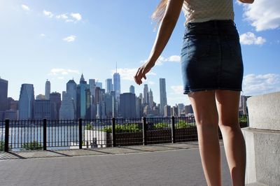 Low section of woman with cityscape against sky