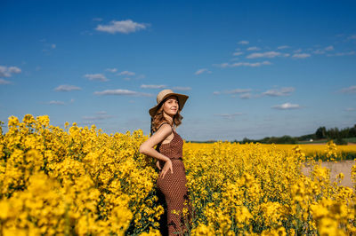 A young girl in a dress and hat is standing in a field