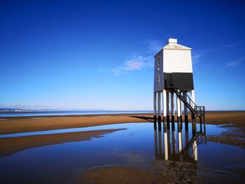 Lighthouse by sea against sky