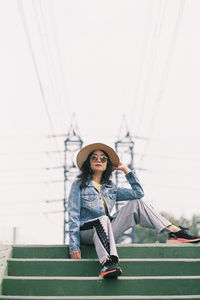 Full length portrait of woman sitting on bridge