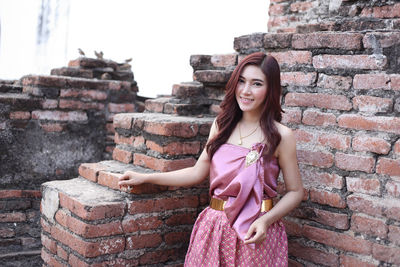 Portrait of woman standing against brick wall