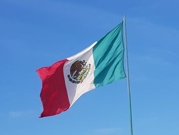 Low angle view of flag against blue sky