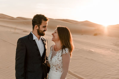 A couple in their wedding dresses in the desert are having fun while posing in the desert. 