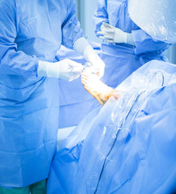 Midsection of surgeon operating patient foot in hospital