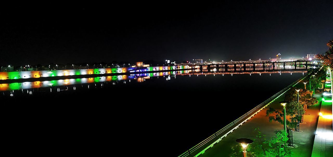 ILLUMINATED BRIDGE OVER RIVER AT NIGHT