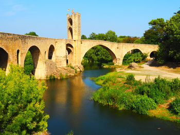 Arch bridge over river against sky