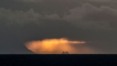 Scenic view of sea against cloudy sky at sunset