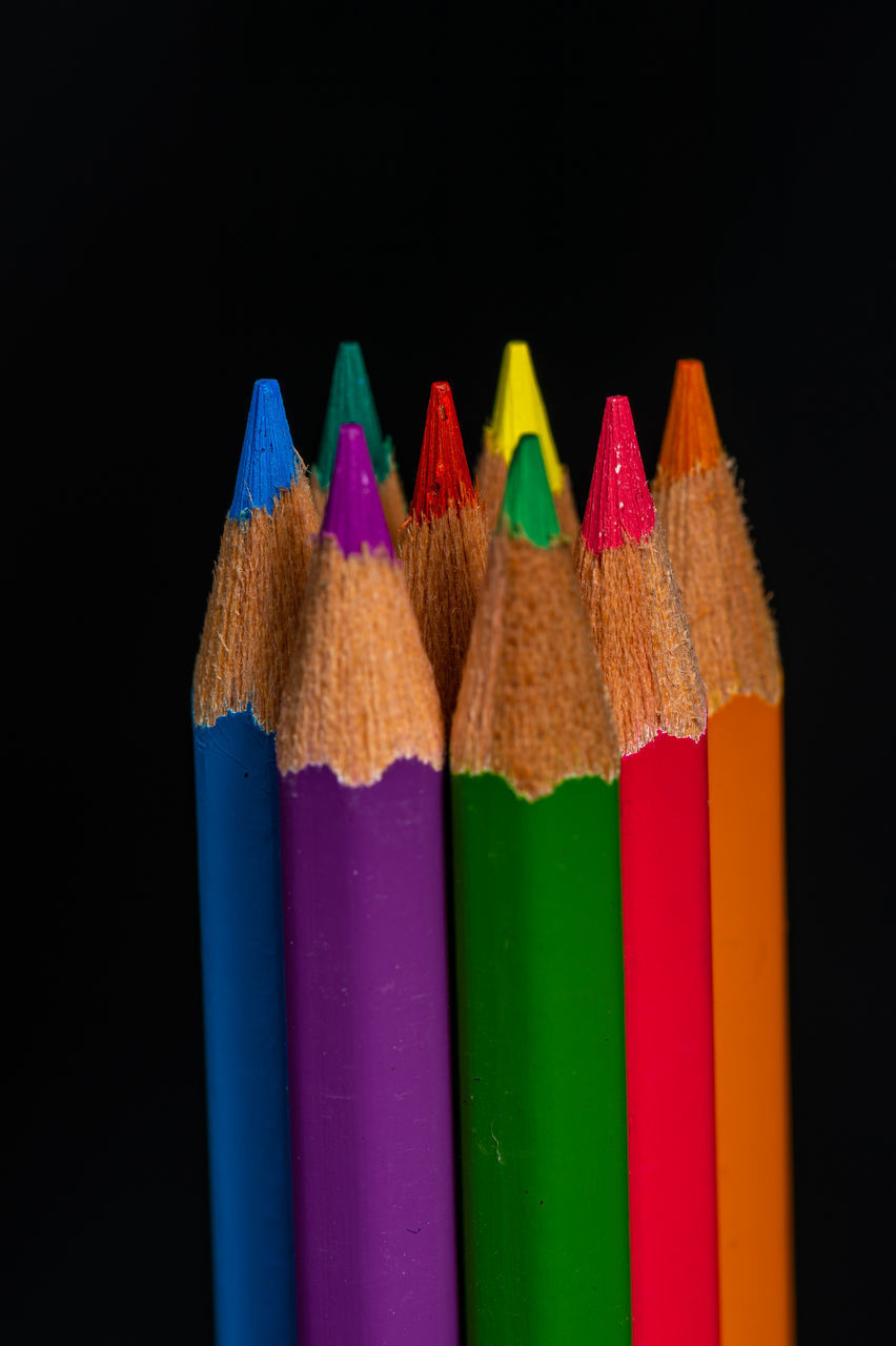CLOSE-UP OF MULTI COLORED PENCILS ON BLACK BACKGROUND