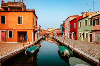 Boats moored in canal amidst buildings in city