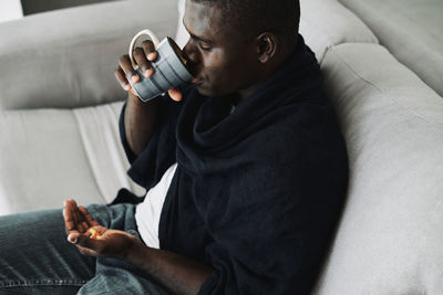 Midsection of man wearing hat while sitting on sofa at home