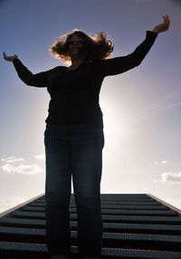 Low angle view of woman standing against sky