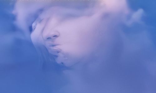 Close-up portrait of young woman against blue sky