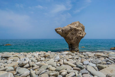 Rocks on shore by sea against sky