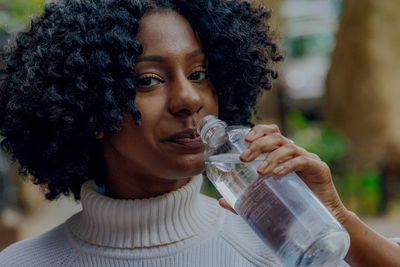 Close-up portrait of smiling young woman drinking water