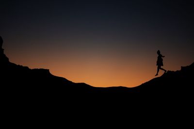 Silhouette man standing on mountain against clear sky