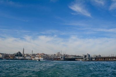 View of city at waterfront against cloudy sky