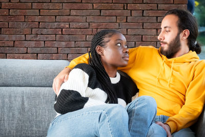 Senior man sitting on sofa against brick wall