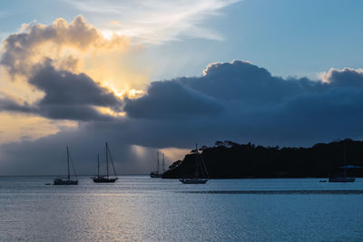 Sailboats in sea against sky during sunset