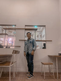 Full length portrait of young man standing at cafe