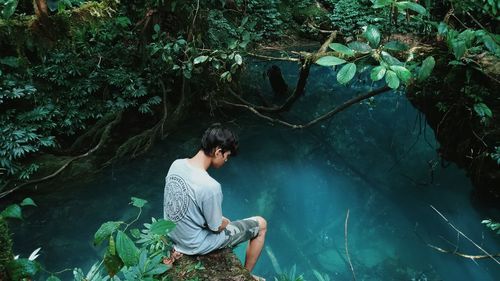 Young man on rock in forest