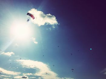 Low angle view of silhouette person paragliding against sky