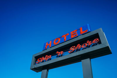 Low angle view of information sign against clear blue sky