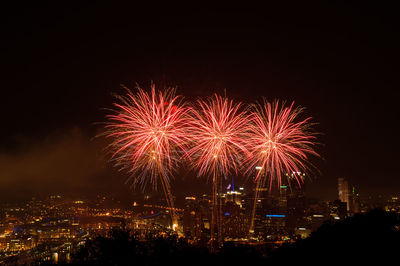 Firework display in city against sky at night