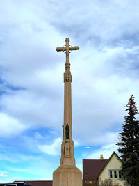 Low angle view of cross by building against sky
