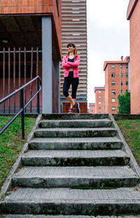 Woman sitting on staircase of building