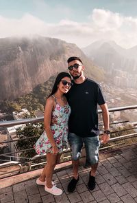 Young couple standing on railing against mountains