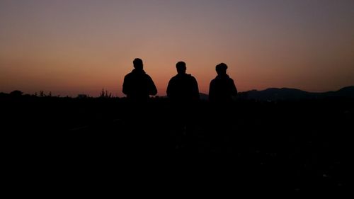 Silhouette people standing on land against sky during sunset