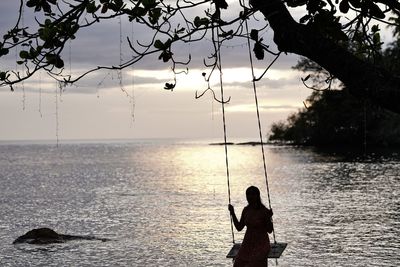 Rear view of woman standing in sea against sky