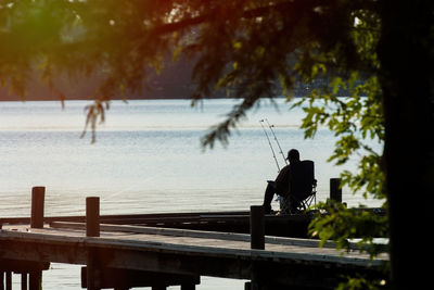 Silhouette man by trees at riverbank