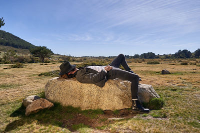 Portrait of young tattoed man lying on a rock in the countryside