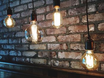 Illuminated light bulb hanging on wall